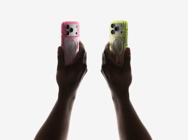 Two CLICK Clear Ombre cases in pink and lime green held aloft by silhouetted hands in soft studio light