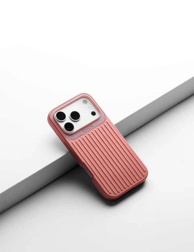Pink CLICK Nova case on a phone, leaning on a gray ledge