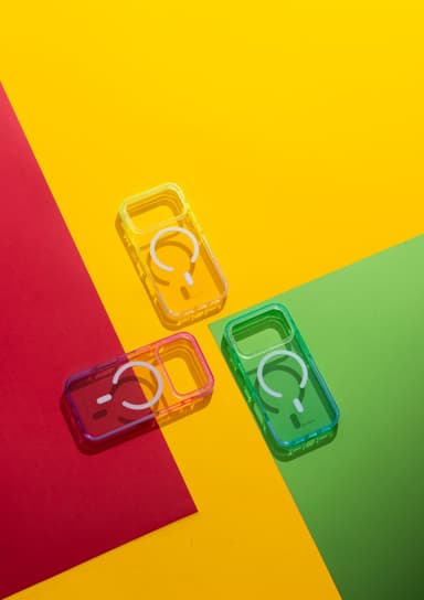 Three CLICK Clear Ombre MagSafe cases styled flat on matching color-block paper in yellow, pink, and green