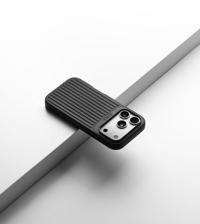 Black CLICK Nova case on a phone, angled on a pale riser