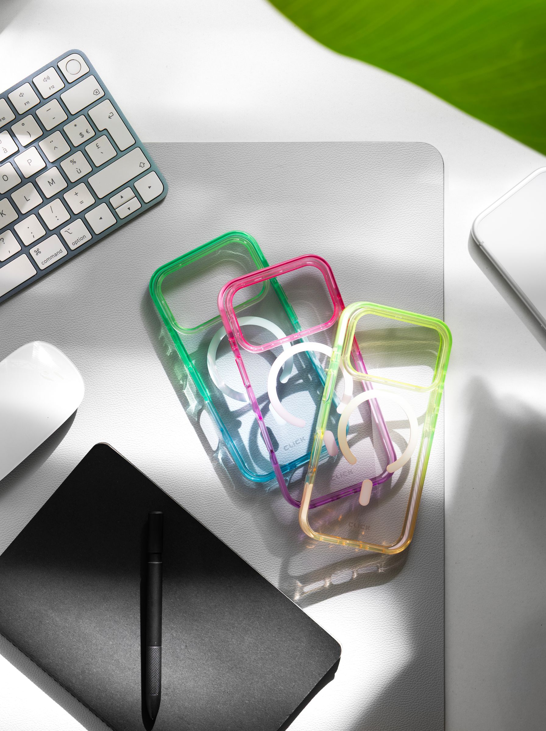 Three empty CLICK Clear Ombre shells with gradient edges on a desk beside a keyboard and notebook